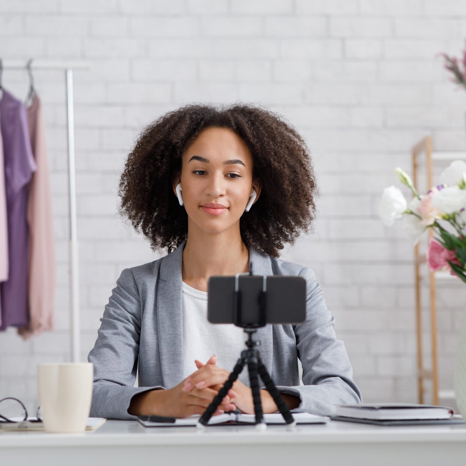 Online fashion blogger advice during self-isolation. Serious african american woman looking at webcam in interior fashion studio at home